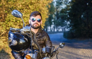 bir adam bir motosiklet ile sakal ve gözlük yolda