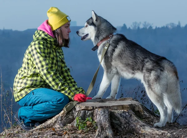 Mädchen sitzt mit Husky-Hund in den Bergen — Stockfoto