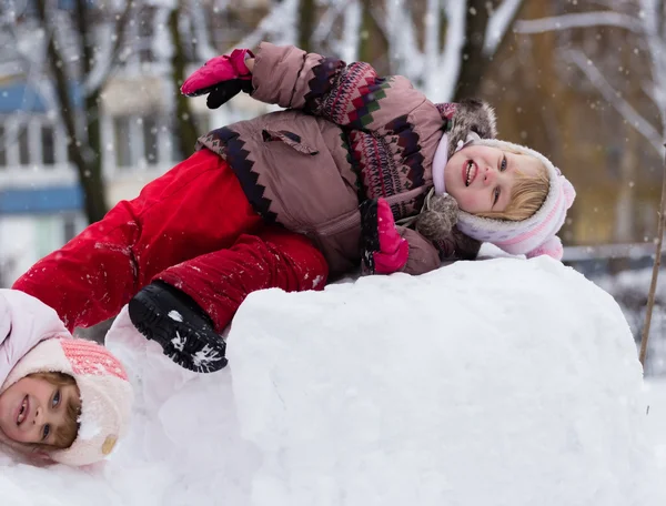 Two funny adorable little sisters building a snowman together in — Stock Photo, Image