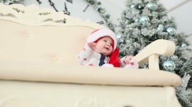 Bebek oturur bir hediye ile bir Noel ağacı yakınındaki