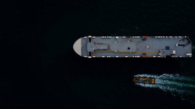 Yuvarlanan gemi yeni arabaları yüklüyor. Denizde yüzen otomotiv konteynır taşıyıcıları, okyanus taşımacılığı büyüklüğünde Roll-on Roll gemisiyle uluslararası ihracat malları ihraç ediyor, gece vakti çekilen fotoğraflar, havadan üst görünüm.  