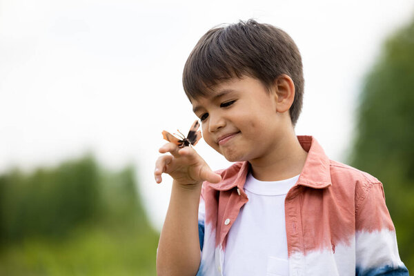 boy with butterfly on hand in the nature background 