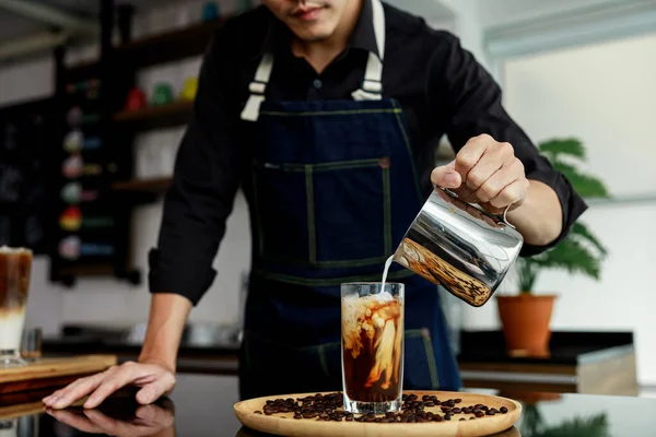 Tayland 'ın seçici odak bulanıklığı arka planında, tahtadan tabağa süt döken birinin eli. 