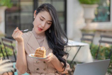 Taylandlı tasarımcılar iş adamları pasta yerken tatsız bir şekilde bahçede dizüstü bilgisayarla çalışıyorlar.