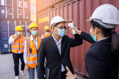 İşçi Mühendis Vücut Sıcaklığı Denetleme Yöneticisi Çalışan konteynır sitesinde kızılötesi termometre tabancalı Covid19 Virüsü