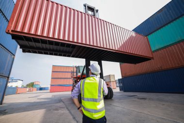 Ustabaşı, uluslararası ithalat ve ihracat için Kargo yük gemisinden konteynır kutusu yükleme işini kontrol ediyor 