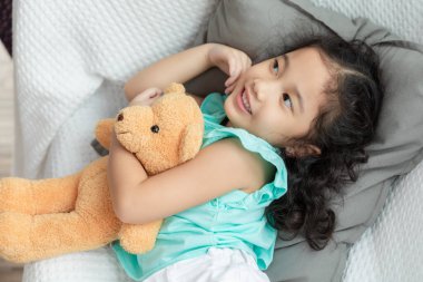 Yatak odasında kahverengi ayılı kız