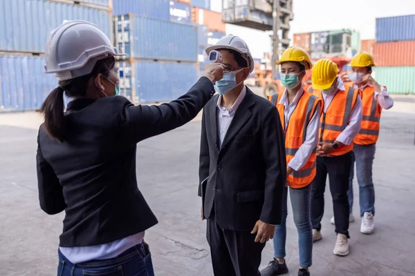 engineer women hold digital thermometer, measure temperature for screen workers with face mask, prevent against infection of Covid-19 outbreak, industrial engineers in line at manufacturing industry factory. Thailand