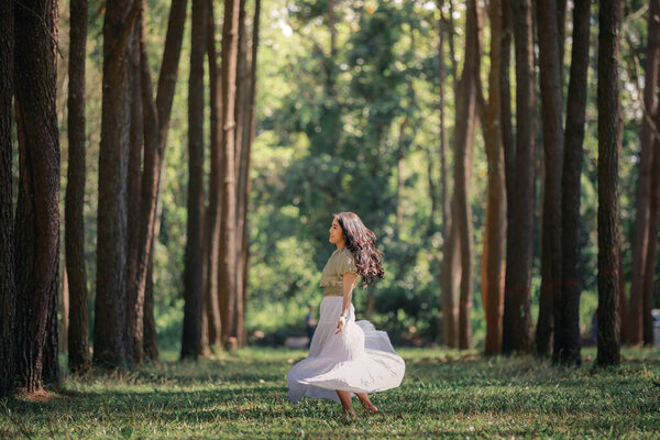 Beautiful asian women girl walking and relaxing in the natural park pine forest, alone nature people concep