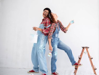 Yom-bear ve ekose gömlekli genç Asyalı çift Tayland 'da yeni bir renge boyamaya yardım ediyor.