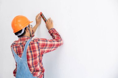 Ekose gömlekli usta mühendis ve turuncu şapkalı ayı bezi beyaz duvar yenileme konseptinde suyu kullanıyor.