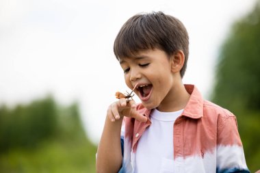 Elinde kelebek olan çocuk doğada yaşıyor. 