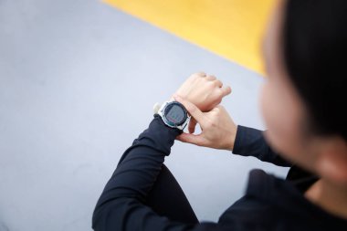 Genç bir kadın sabah koşmadan önce zaman zaman bileğindeki zamanlayıcıya bakıyor..