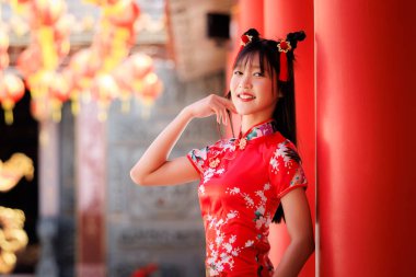 Profesyonel sinemada, neşeli saç stili olan güzel bir kadının yeni yılı kutlarken sıcacık gülümsemesi canlı kırmızı sütunlar ve parıldayan fenerler yaratıyor.