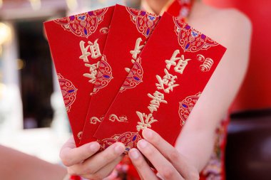 Ay 'ın yeni yıl kutlamaları sırasında canlı kırmızı zarflar ya da Hongbao' yu altın kaligrafiyle sunan ellerinizi kapatın.