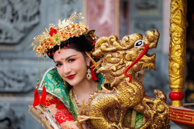 Canlı bir tarihi kostümün içindeki zarif bir sanatçı antik geleneği somutlaştırıyor. Efsanevi bir altın ejderha tutuyor. Kültürel bir kutlama sırasında gücün ve talihin sembolü.