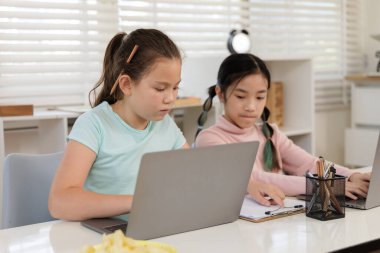 İki kız, dijital çağın her yerinde eğitimin nasıl ulaşılabilir olduğunu gösteren bir sınıfta veya evde çevrimiçi derslerine odaklanmış durumdalar..