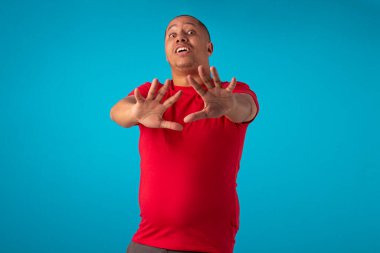 Mavi arka planda kırmızı tişörtlü bir yetişkin, çeşitli yüz ifadeleri yapıyor..