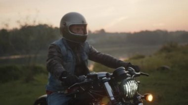 Parkta motosiklet süren kask takan bir motorcu.