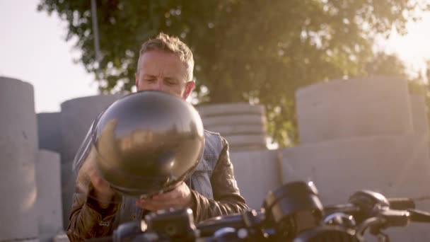 准备让一些摩托车探险英俊的摩托车手把他的摩托车头盔与太阳光为背景 — 图库视频影像
