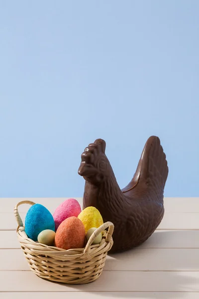 Galinha de chocolate de Páscoa e ovos coloridos sobre uma mesa branca — Fotografia de Stock