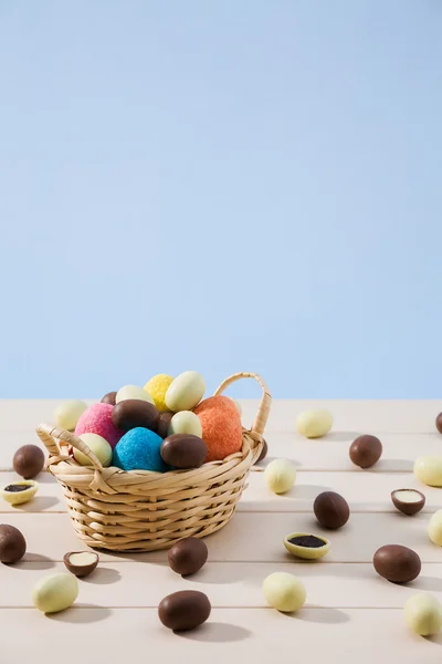 Ovos de chocolate de Páscoa em uma pequena cesta com fundo azul — Fotografia de Stock