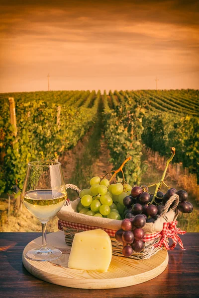 Склянка білого вина перед виноградником на заході сонця — стокове фото