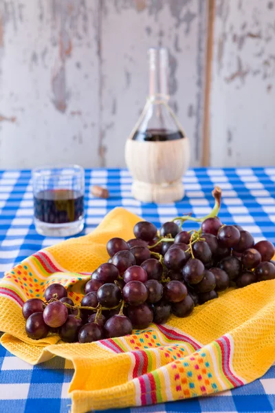 Um bando de uvas vermelhas e um copo de vinho tinto com um balão de vinho — Fotografia de Stock