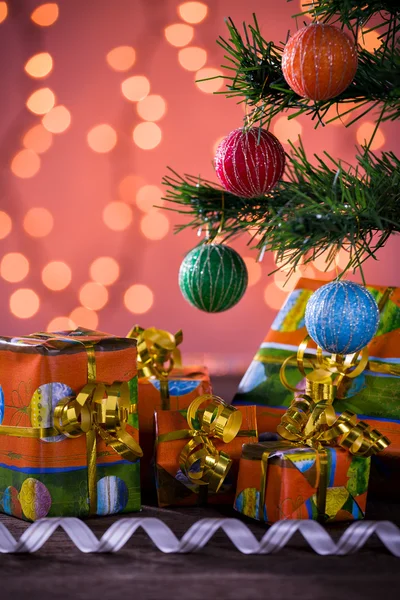 Christmas gifts with blurred lights and ribbon under the tree — Stock Photo, Image