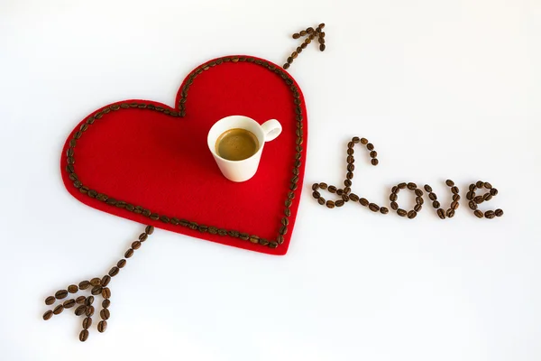 Šálek kávy na červenou plstí srdce s šipkou a láska — Stock fotografie