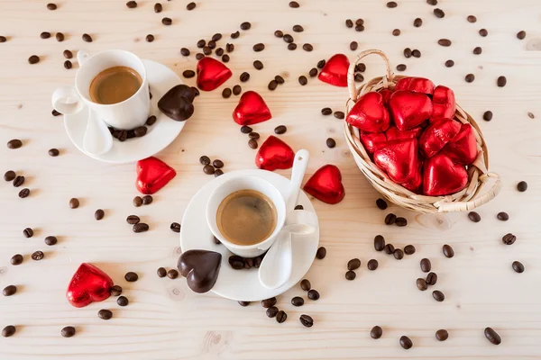 Красные шоколадные сердечки в маленькой корзине и две чашки кофе — стоковое фото