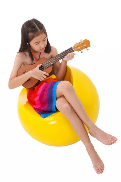 Kislány ruha ül a székre ukulele játszik — Stock Fotó