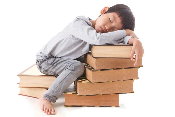座っていると書籍のスタック上で眠っているアジアのかわいい男の子. — ストック写真
