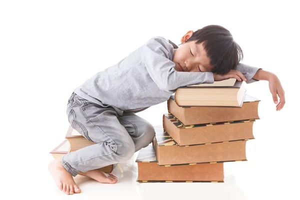 Aziatische schattige jongen zitten en slapen op stapel boeken. — Stockfoto