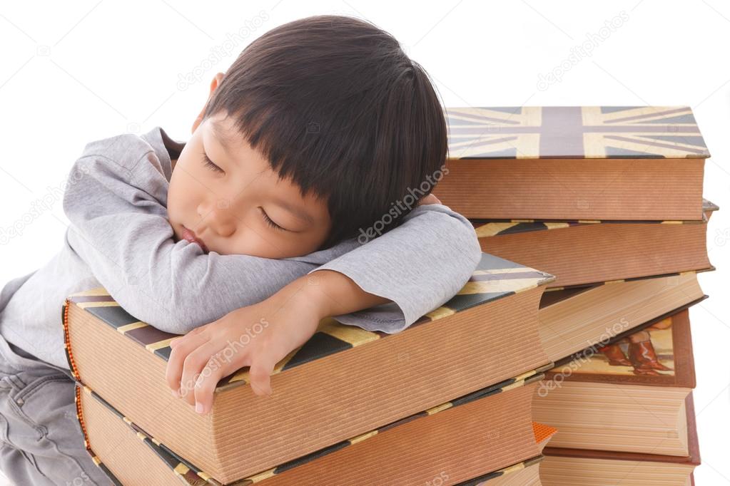 Asian cute  boy sleeping on stack of books.