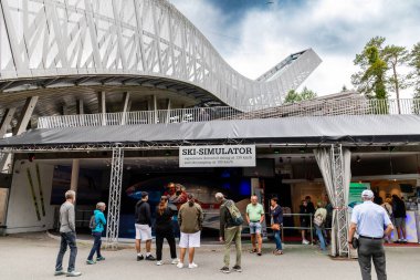 Oslo, Norveç-11 Ağustos 2025: Ziyaretçiler, yüksek hızlı kayak ve kontrollü bir uçuşta kayak simülatörü deneyimlemek için kayak atlama yapısının altında toplandılar.