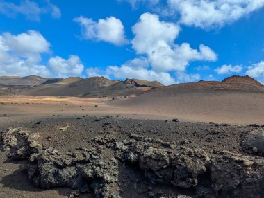 İspanya, Kanarya Adaları, Lanzarote-6 Şubat 2026 Engin volkanik çöl engebeli lav kayaları ve yuvarlanan tepeler parlak mavi gökyüzü altında.