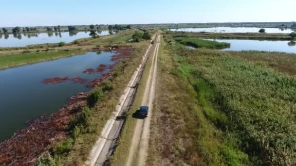 夏の釣り場の土壌ダム道路上の移動車の空中ショット夏の晴れた日に釣り場のドニプロ川流域を切断未舗装のダム道路上の乗馬車の鳥の目のビューを刺激します 良くも悪くも — ストック動画