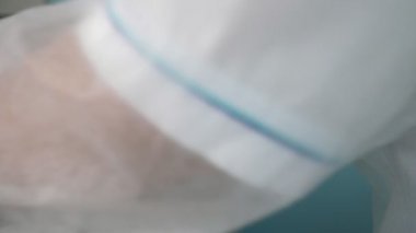 Elleri lastik eldiven içinde, ofisteki bir raftan idrar örnekleri alıyor. Profesyonel olarak yakın plan, beyaz lastik eldivenli, havadar bir hastane ofisindeki beyaz plastik bir raftan idrar örnekleri alıyor..