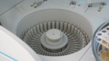 Santifüjden kan örnekleri alan erkek doktor elleri. Plastik eldivenli bir eczacının erkek ellerine yakın çekim. Hastane ofisindeki plastik bir santrifüjden alınan kan örnekleriyle dolu düz kutular..