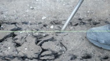 Yıkım çekicinin asfalta saplanması ve ağır çekimde kırılması şaşırtıcı bir şekilde kaya matkabının metalik keskisinin asfalta saplanması ve titreşimleriyle onu kırması. Erkek botu yavaş çekimde yakınlarda görüldü.