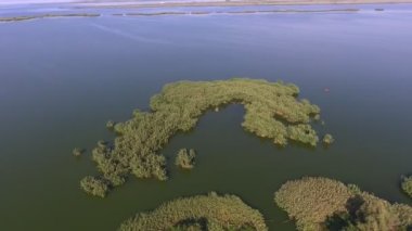 Yazın güneşli bir günde güneşli bir günde, pek çok ağaç, çalı ve çalı ile kaplı pek çok dar körfez ve adacıklarla dolu engebeli bir arazinin muhteşem kuş bakışı manzarası arasında kalan kıvrımlı körfezlerden ve adalardan vahşi bir manzara. İyi görünüyor.