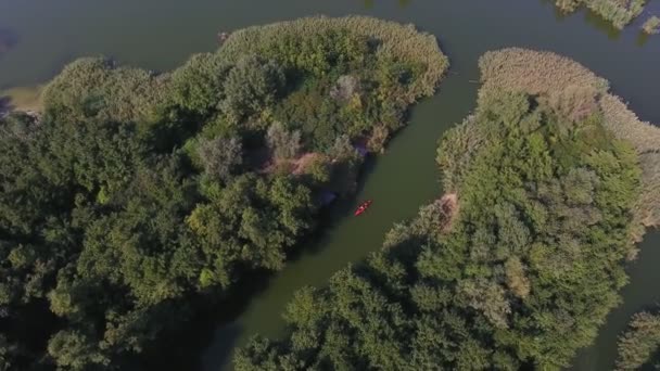 小红船在两个绿岛之间的弯曲海湾中漂浮 令人印象深刻的360度鸟瞰着一艘小红船在两个小湾之间穿行 在夏天 这两个小湾被许多树木 灌木和镇静剂覆盖着 — 图库视频影像