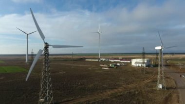 Bulutlu bir günde dönen pervaneli birkaç rüzgar enerjisi sütunun havadan çekilmiş görüntüsü üç hareketsiz beyaz enerji direğinin hareketsiz kanatları ve motorlarıyla yazın bulutlu bir günde deniz kıyısında rüzgar enerjisi elde etmesinin heyecanlı bir görüntüsü..