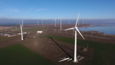 Yazın rüzgarda süzülen enerji direklerinden oluşan bir çizginin havadan çekilmiş görüntüsü. Yazın güneşli bir günde deniz kenarında rüzgâr enerjisi toplayan dönen dönen büyük kanatlı uçan beyaz sütunların kuş bakışı görüntüsü etkileyici.. 
