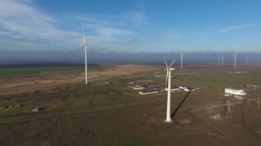 Deniz kenarındaki hareketsiz bıçaklarla sıralanmış rüzgar enerjisi sütunlarının havada görüntüsü iyimser kuş bakışı büyük bıçaklı hareketsiz beyaz sütunlar ve yazın güneşli bir günde rüzgâr enerjisi toplayan dönen bir enerji sütunu.. 