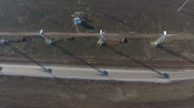 Yazın üç yüksek rüzgar enerjili sütunun havadan çekilmiş görüntüsü. Güneşli bir yaz gününde üç yüksek beyaz sütun döner bıçaklarla rüzgâr enerjisi topluyor. Neşeli görünüyorlar..