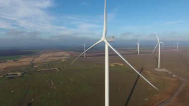 Sahil kenarındaki hareketsiz bıçaklarla sıralanmış rüzgar enerjisi sütunlarının havadan çekilmiş görüntüsü. Güneşli yaz günlerinde deniz kenarında rüzgar enerjisi toplamak için büyük pervaneleri ve büyük motorları olan hareketsiz beyaz sütunlar.. 