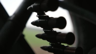 Bahar mevsiminde devriye helikopterine 12.7 mm 'lik makineli tüfek kurşunuyla titreyen bir kartuş bandına yakın çekimde uçan bir helikopterdeki makineli tüfeğe sabitlenmiş mermilerle dolu muharip mermi bandı. Modern ve istikrarlı görünüyor..