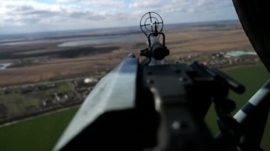 Ön görüşlü güncel makineli tüfekler, hava bulutluyken helikopterde uçan nesnelere sabitlenmiş, karadan karadan karaya bakan, modern bir makineli tüfeğin, karadan görünüşü ve yuvarlak bir görüşü olan helikopter objelerini hedeflemektedir.